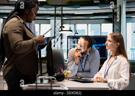Teamworking colleagues speeding up tasks by following AI language model suggestions in office. Team of engineers doing brainstorming, relying on artificial intelligence LLM assistant to fix mistakes Stock Photo