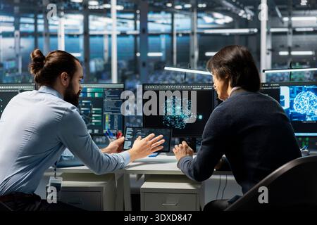 Technicians in data center installing upgraded server racks systems helped by AI technology. Server hub workers upgrading enterprise networks hardware using artificial intelligence Stock Photo
