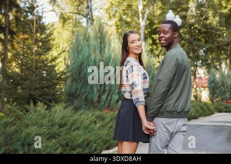 Couple Enjoying a Walk in a Lush Park Setting During a Sunny Afternoon Stock Photo