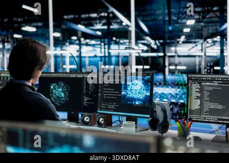 Data center admin running simulations for AI driven forecasting, tracking performance. Server room IT employee integrating artificial intelligence APIs into software platforms Stock Photo