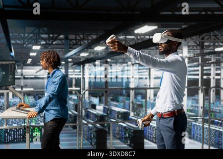 Data center admin using VR glasses to monitor neural network AI systems. Server hub specialist using virtual reality tech to oversee equipment powering machine learning processes, configuration. Stock Photo