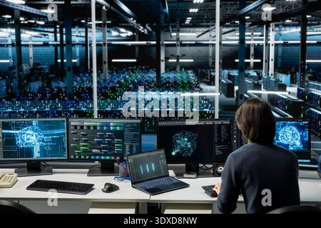 IT expert using PC in high tech server hub with gear supporting deep learning scientific simulations. Computer scientist in data center doing checkup on rackmounts using neural networks Stock Photo