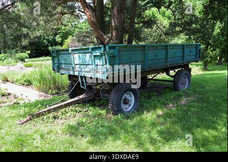 Old tractor trailer in the autumn forest.Old abandoned rusty tractor trailer. Stands on a green lawn.Old tractor trailer in the village yard Stock Photo