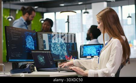 Junior developer in office integrating AI machine learning systems to streamline workflows. Young employee uses neural networks artificial intelligence, technology overload concept, camera A Stock Photo
