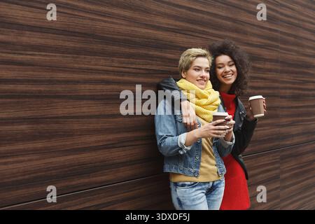 Two Friends Enjoy Warm Drinks in a Modern Cafe Setting While Smiling and Chatting With Each Other Stock Photo