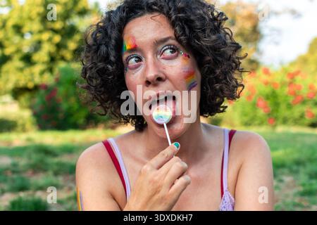Young woman enjoying rainbow lollipop celebrating pride Stock Photo