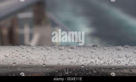 Raindrops on Metal Handrail of a Ship Deck with Blurred Sea Background Stock Photo
