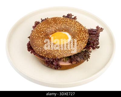 Bagel with egg, sausage, and fresh herbs on a plate. Isolated on white background, top view. Stock Photo