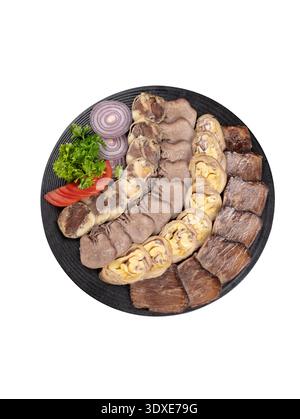 Assorted sliced cold cuts and sausages arranged on a black plate. Isolated on white background, top view. Stock Photo