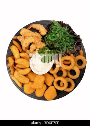 Assorted fried seafood and snacks on a black plate with herbs. Isolated on white background, top view. Stock Photo