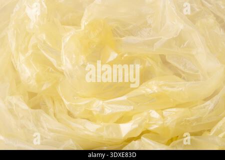 Crumpled yellow plastic material forming an abstract background texture. Showing translucent, synthetic, and reusable plastic packaging Stock Photo