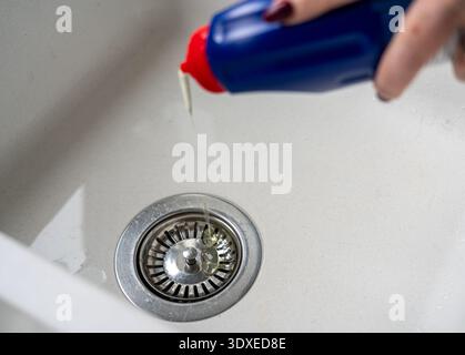 Close view of bleach being poured into a kitchen sink Stock Photo