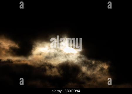 Sun breaking through dark storm clouds Stock Photo