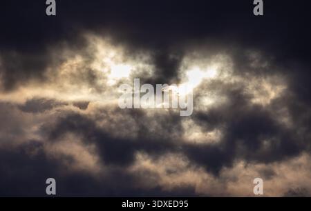 Sun breaking through dark storm clouds Stock Photo