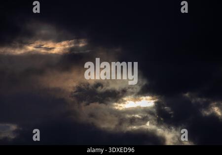 Sun breaking through dark storm clouds Stock Photo