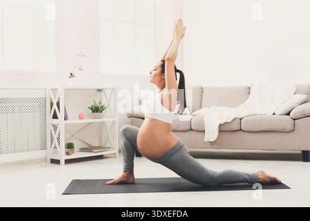 Pregnant Woman Doing Yoga in Living Room Setting With Natural Light in Morning Hours Stock Photo
