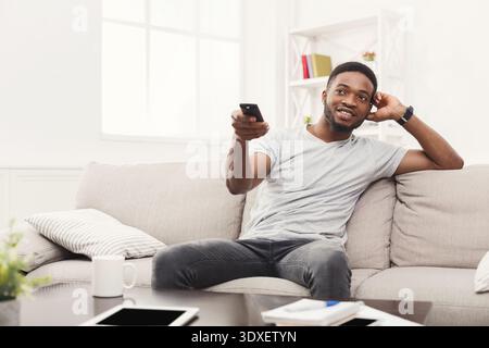 Relaxing at Home While Watching TV From a Comfy Couch With a Remote Control in Hand Stock Photo