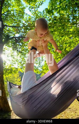 Parent and Baby Relaxing in Hammock Outdoors Stock Photo