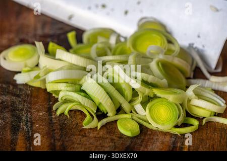 Close up of freshly sliced leek arranged on a rustic wooden cutting board. Stock Photo