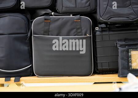Black travel and laptop bags displayed on shelf in store. Modern backpacks and business luggage concept, retail shopping and travel accessories Stock Photo