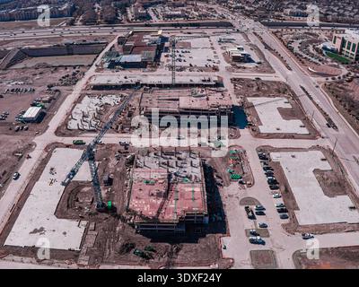 Aerial view of construction sites and cranes casting long shadows on freshly laid concrete foundations, Frisco, Texas, United States. Stock Photo