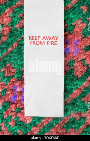 Clothes label text keep away from fire over colorful knit wool fabric background Stock Photo