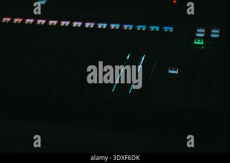 Riga, Latvia - February 28, 2026:Low-key close-up of a professional audio mixing console with illuminated LED faders in a dark studio environment. Ide Stock Photo