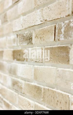 A close-up, angled view of a textured brick wall with shallow depth of field. Soft, bright light highlights the warm neutral tones of beige, cream, an Stock Photo