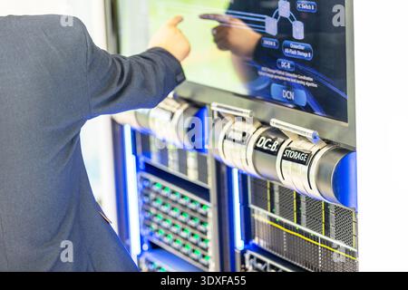 IT specialist operating touchscreen control panel in modern data center, monitoring servers, network storage and cloud infrastructure for secure enter Stock Photo