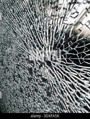 Shattered glass pattern background. Close-up of shattered safety glass featuring a radial impact pattern. Web of fractures creates a dramatic texture. Stock Photo
