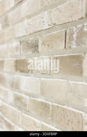 Angled view of a textured brick wall with shallow depth of field. Soft, bright light highlights the warm neutral tones of beige, cream, and tan. Perfe Stock Photo