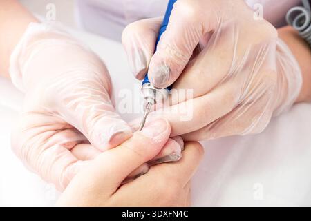 Hardware processing of the nail plate close-up. Flame cutter with red mark for cuticle processing. Manicure process in a beauty salon. Hygiene procedure Stock Photo