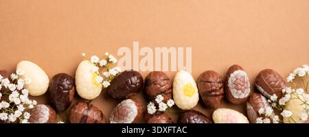 Colorful Easter eggs arranged with delicate white flowers on a brown background for festive decoration Stock Photo