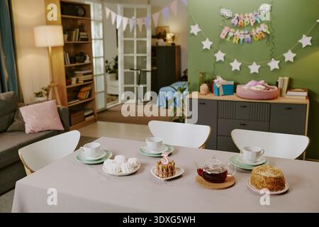 Birthday Table Setting Featuring Cake and Sweets in Decorated Living Room Stock Photo