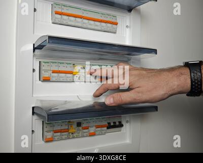Kirov, Russia - January 03, 2026: A hand is seen switching on circuit breakers in an electrical panel for electricity control and safe power distribut Stock Photo