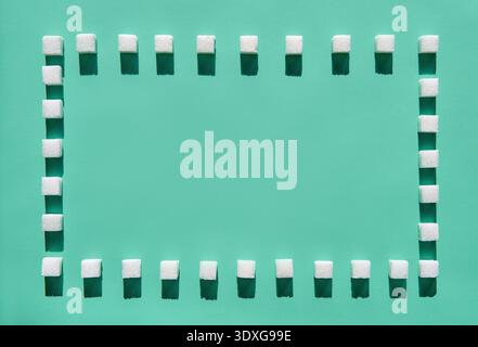 Minimal creative layout of sugar cubes forming square frame on green pastel background Stock Photo