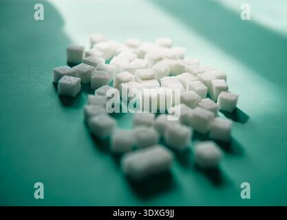 Closeup of white sugar cubes on green surface with strong light and soft shadows Stock Photo