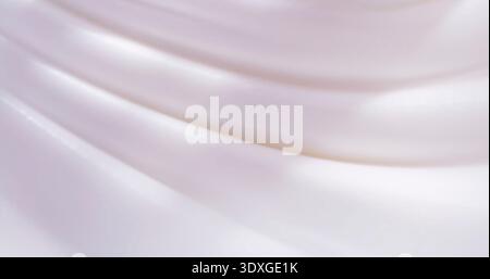 Smooth white fabric draped in soft waves under gentle light in a simple setting during daytime hours Stock Photo