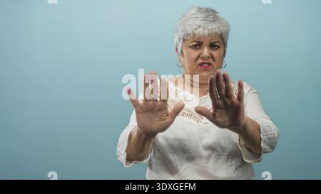 Woman grey hair plus size wearing white blouse holding hands up palms out in stop gesture in studio; disgust rejection. Stock Photo