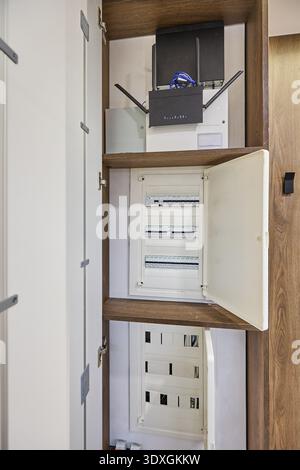 Open built-in closet showing Wi-Fi router, wiring and electrical distribution board with circuit breakers, organized inside a modern apartment cabinet Stock Photo