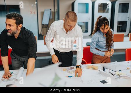 Team of professionals collaborates on blueprints and plans in a modern office space Stock Photo