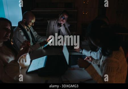 Business meeting with a diverse team collaborating around a table with laptops and tablets Stock Photo