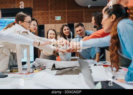Diverse team of business professionals joining hands in a collaborative office meeting Stock Photo