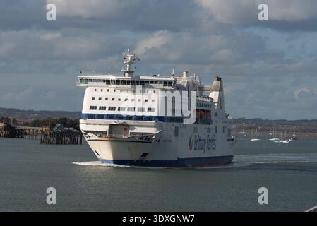 Portsmouth England UK. 28.02.2026. A large white passenger ferry with blue trim sails away from the harbor, leaving a wake behind it under a dramatic Stock Photo