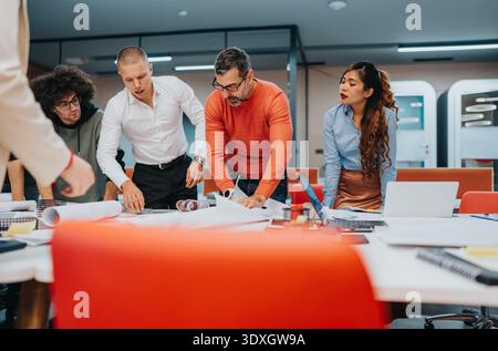 Focused team of diverse professionals collaborates over plans and documents in a modern office Stock Photo