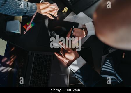 Business team at a desk collaborating, writing notes, and using laptop in a modern office Stock Photo