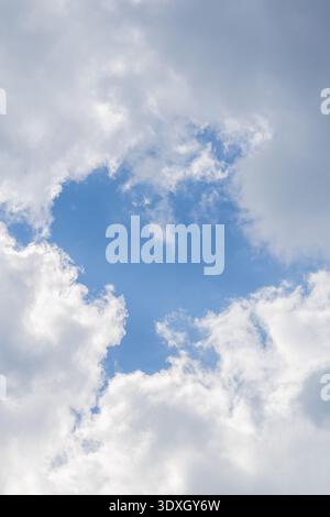 Blue sky opening between fluffy clouds creating natural copy space, serene cloudscape, Province of Luxembourg, Belgium. Stock Photo