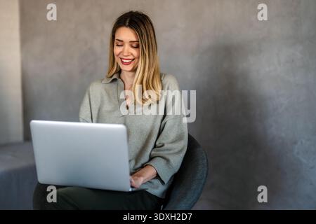 Young female designer, freelancer working in the office. Female using laptop to searching info. Stock Photo