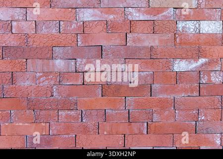 Detailed close-up of a rustic red brick wall. The bricks have a unique embossed, scale-like pattern and show signs of weathering with white stains. A Stock Photo