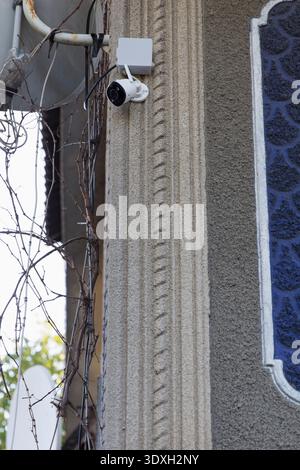 View of a modern security camera installed on a textured, fluted concrete wall. Neutral grey and white colors. Concept for surveillance, safety, monit Stock Photo